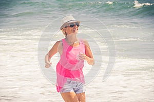 Happy cheerful woman running along the beach against the ocean