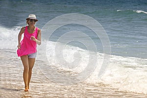 Happy cheerful woman running along the beach against the ocean