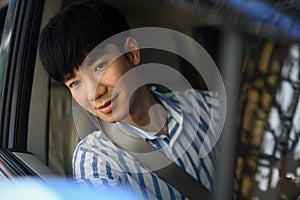 Happy cheerful young Asian man wearing casual outfit driving during summer vacation road trip