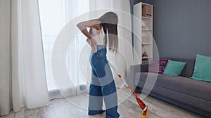 Happy and Cheerful young beautiful woman cleans floor with mop and talks on phone