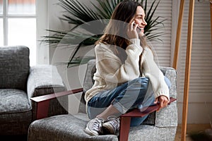 Happy cheerful young woman talking on the phone at home