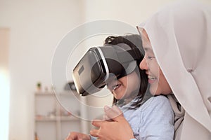 Happy cheerfull Asian muslim mother and daughter playing games on vr glasses