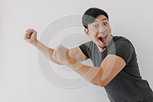 Happy and cheering funny face Asian man in black t-shirt isolated on white.