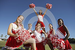 Happy Cheerleaders Holding Pompoms On Field