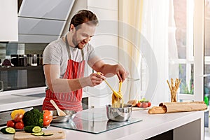 Happy chef cooking noodles in kitchen photo