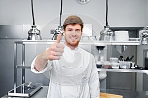Happy chef at restaurant kitchen showing thumbs up