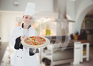 Happy chef showing the pizza in the kitchen