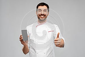 happy chef with smartphone showing thumbs up