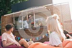 happy chef working in food truck and smiling to young