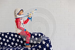 Happy child astronaut playing with toy rocket at home