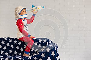 Happy child astronaut playing with toy rocket at home