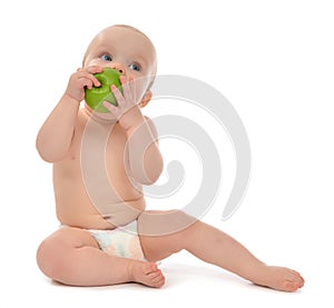 Happy child baby boy sitting in diaper and eating green apple