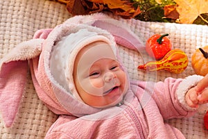 Happy child baby lying in autumn fall park with yellow orange leaves trees