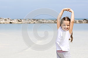 Happy child on the beach. Paradise holiday concept, girl seating on sandy beach with blue shallow water and clean sky