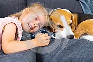 Happy Child with beagle dog lying on couch