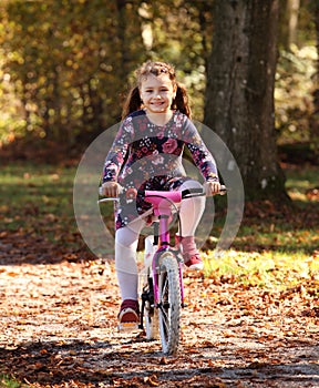 Happy child on bike in autumn forest