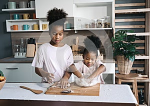 Happy child black skin thresh flour with rolling pin in kitchen