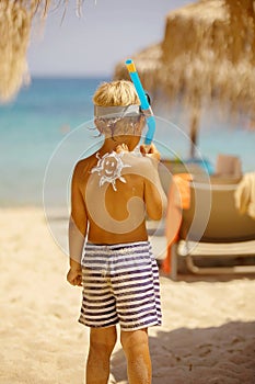Šťastný chlapec na pláž aplikován slunce obrazovka těší,. 