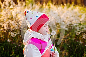 Happy child blowing dandelion outdoors