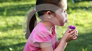 Happy child blowing soap bubbles in park