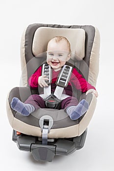 Happy child in booster seat for a car in light background