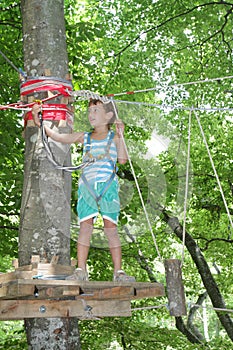 Happy child boy in adventure park in safety equipment