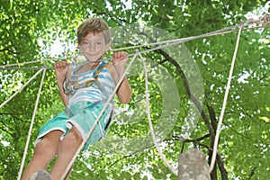 Happy child boy in adventure park in safety equipment