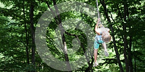 Happy child boy in adventure park in safety equipment