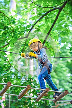 Happy child boy calling while climbing high tree and ropes. Child climbing on high rope park. Cute child boy. Toddler