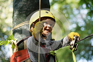 Happy child boy calling while climbing high tree and ropes. Happy little child climbing on a rope playground outdoor