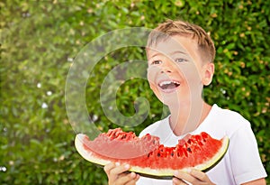 Happy child boy is eating a red juicy watermelon. Caucasian kid smiling and having fun. Concept of healthy food.