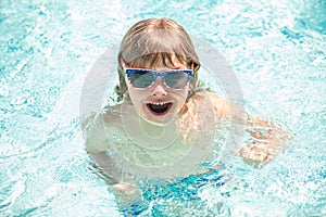 happy child boy in glasses swimming in pool, summer vacation