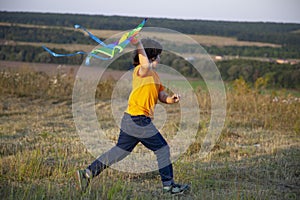 Happy child boy play with a kite running on summer meadow