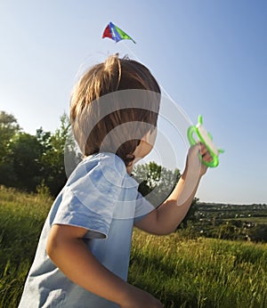 Happy child boy play with a kite running on summer meadow