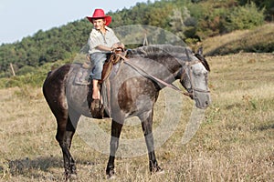 Happy child boy riding horse on nature