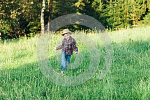 Happy child boy running on meadow in summer