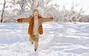 happy child boy runs through the winter snow park