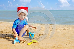 happy child boy in santa hat playing with toys for sand