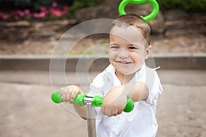 Happy child boy on a trike in the park