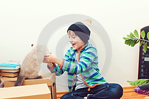 Happy child and cat having fun together at moving day in new home