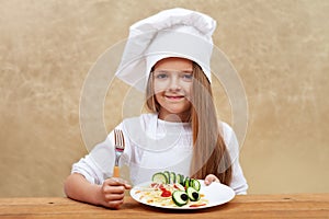 Happy child with chef hat and decorated pasta dish