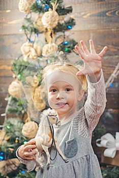 Happy child with a Christmas present on wooden background. Joyful baby looking at camera in christmas at home. Winter