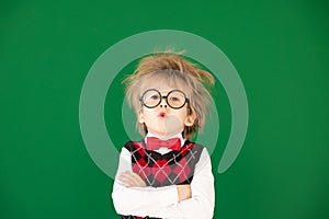 Happy child in class against green chalkboard