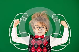 Happy child in class against green chalkboard