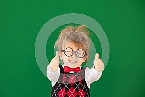 Happy child in class against green chalkboard