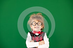 Happy child in class against green chalkboard