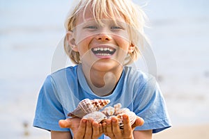 Happy child with collection of shells at beach