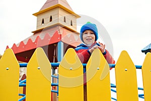 Happy child on colorful castle playground. Cute little boy playing outdoors in cold autumn time. Happy and healthy childhood.