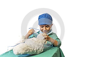 Happy child disguised as a surgeon playing doctor operating on a teddy bear