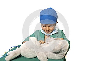 Happy child disguised as a surgeon playing doctor operating on a teddy bear